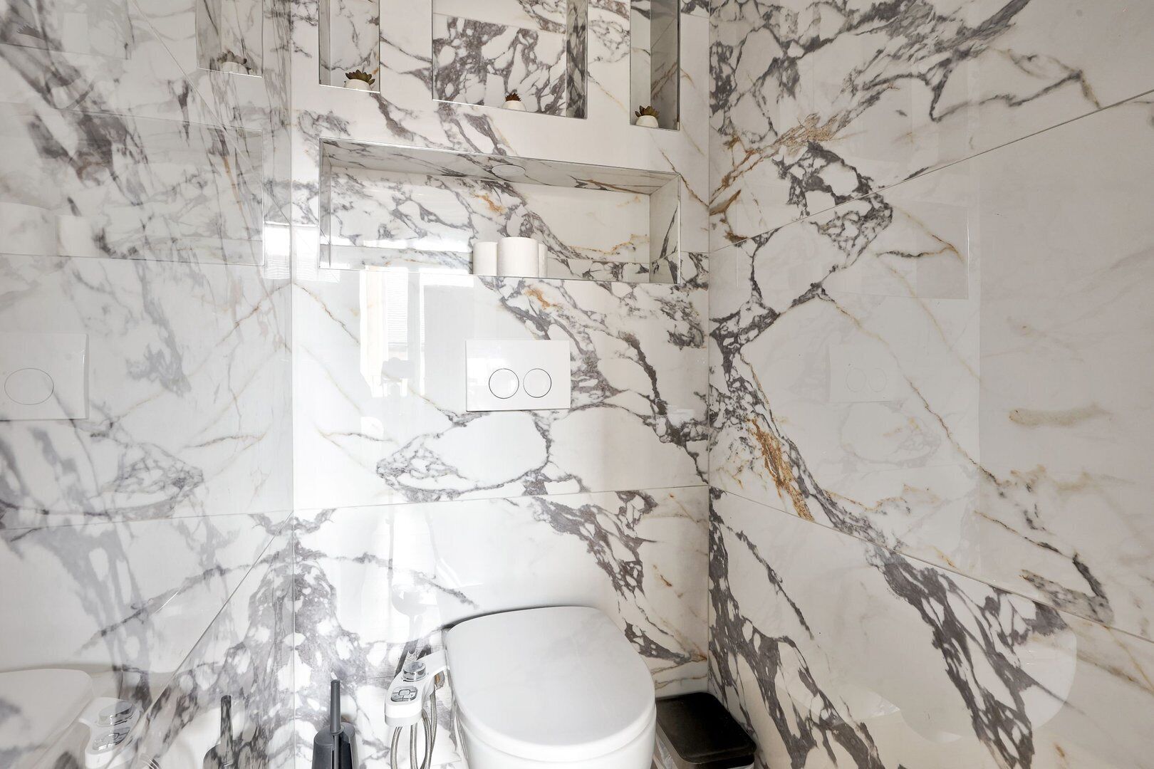 A bathroom with marble walls and a white toilet.
