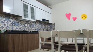 A kitchen with white cabinets, a tiled backsplash, and a dining area with white chairs. - J&J guest house (Hanoi)