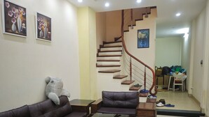 A living room with a sofa, coffee table, and a staircase leading to a hallway. - J&J guest house (Hanoi)