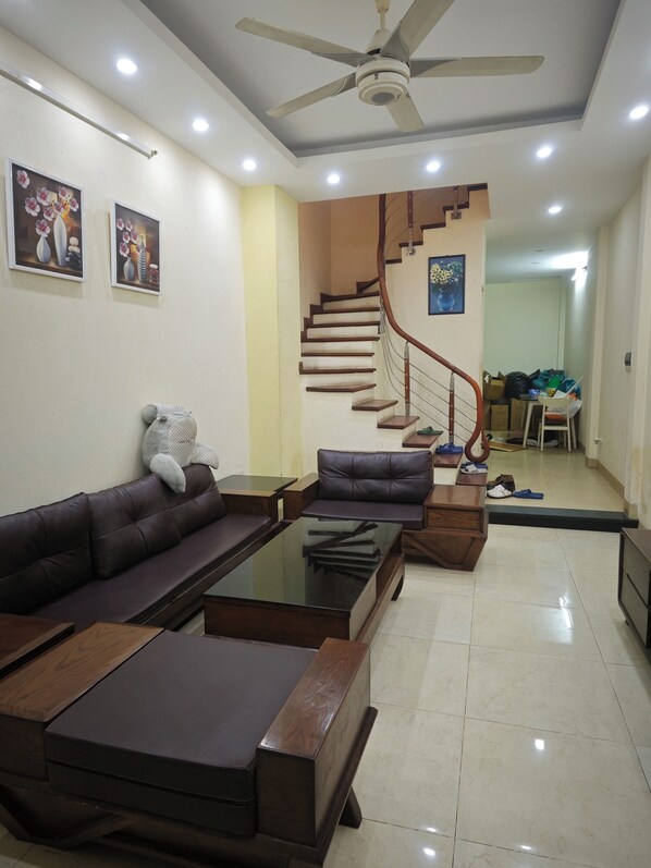 A living room with a sofa, coffee table, and a staircase leading to a hallway.