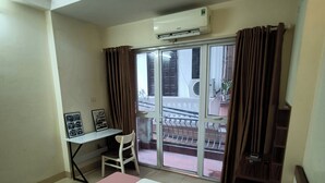 A hotel room with a bed, a desk, and a view of the outside balcony. - J&J guest house (Hanoi)