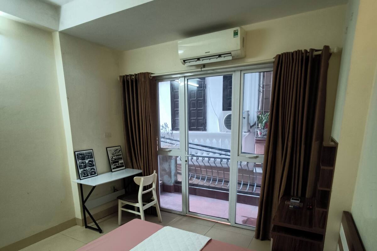 A hotel room with a bed, a desk, and a view of the outside balcony.