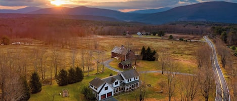 An aerial view of a rural landscape with a large house, barns, and a winding road.