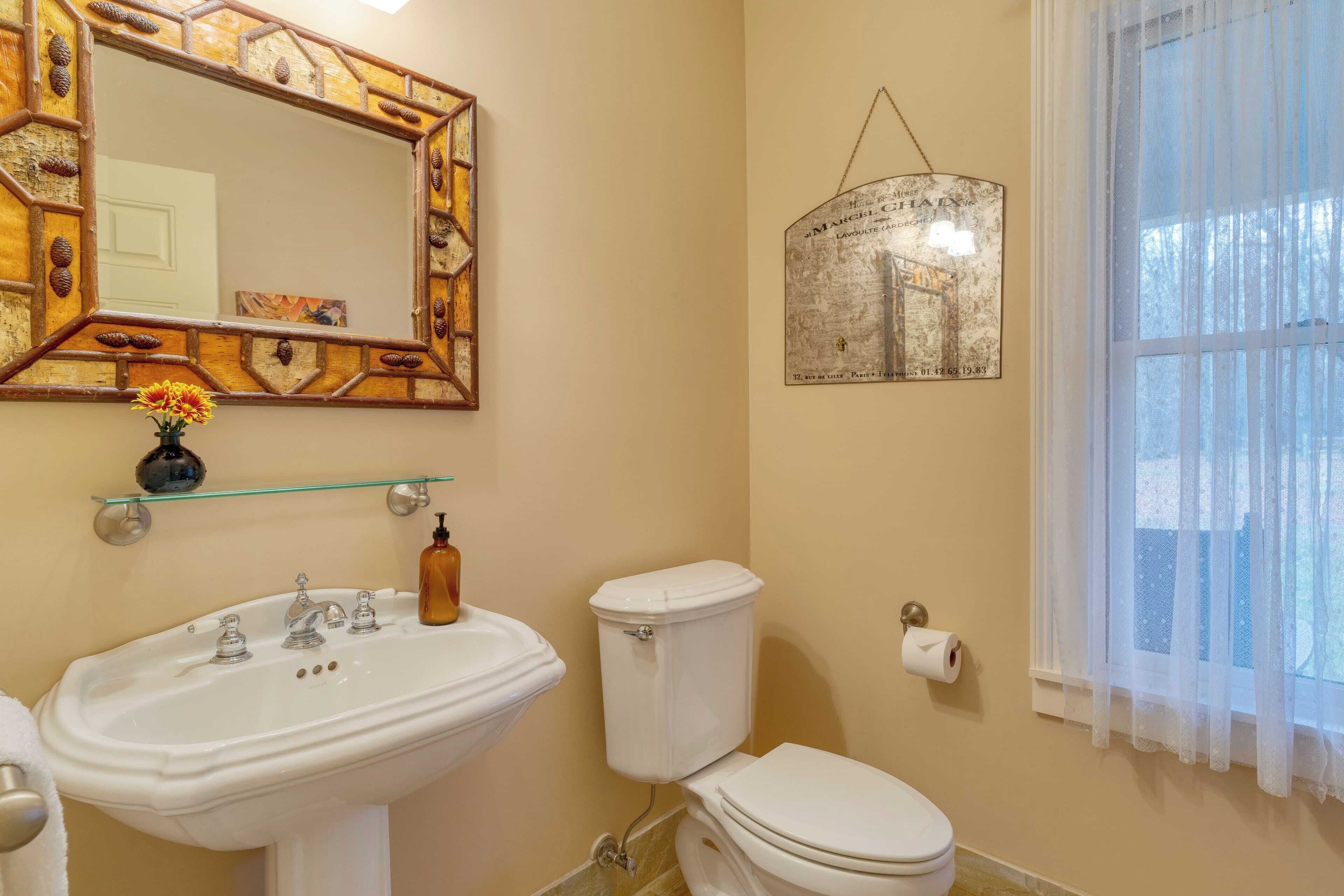 A bathroom with a white sink, toilet, and a mirror with a decorative frame.