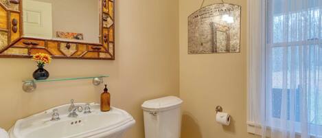 A bathroom with a white sink, toilet, and a mirror with a decorative frame.