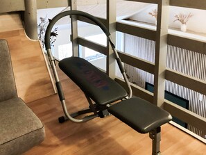 A gym with a stationary bike, a grey couch, and a wooden floor. - 4 Star Holiday Home in Vaeggerlose (Vaeggerlose)