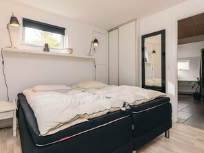 A modern bedroom with a bed, bedside lamps, a window, and a mirror. - 4 Star Holiday Home in Vaeggerlose (Vaeggerlose)