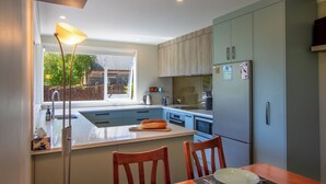 Une cuisine moderne dotée d’un grand îlot central, de meubles en bois et d’un réfrigérateur.