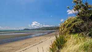 Une plage avec un ciel dégagé et des montagnes à l’horizon.