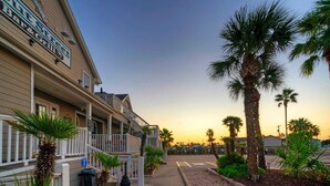 A hotel with a bar and grill, a covered outdoor seating area, and palm trees.