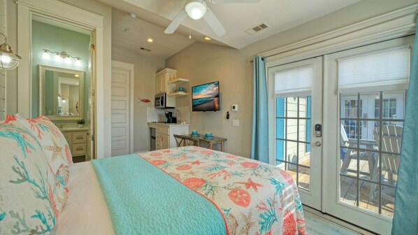 A bedroom with a bed, a bathroom with a mirror, a kitchenette, and a sliding glass door to the outside. - Sailfish at Trout Street Waterfront Escape + Patio Walk to Port A Nightlife (Port Aransas)