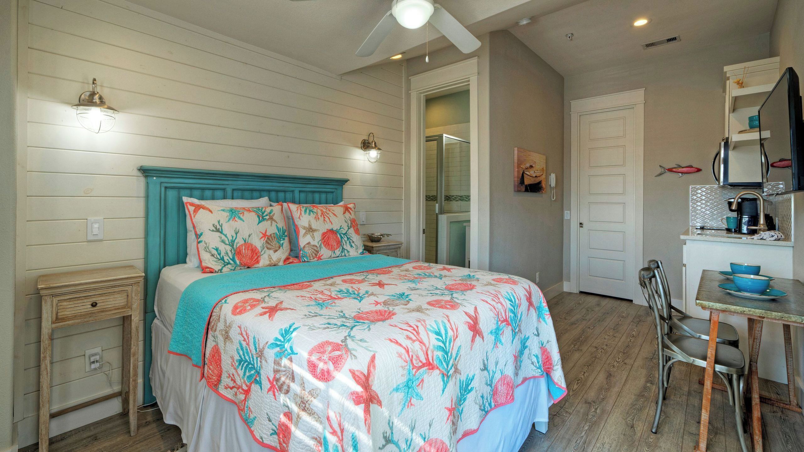 Une chambre comprenant un lit, une table de chevet, une chaise, un bureau et un coin cuisine.
