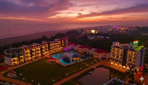A hotel with multiple buildings, a swimming pool, and a view of the sea.