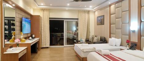 A hotel room with a large bed, a desk, a TV, and a sliding door to a balcony.