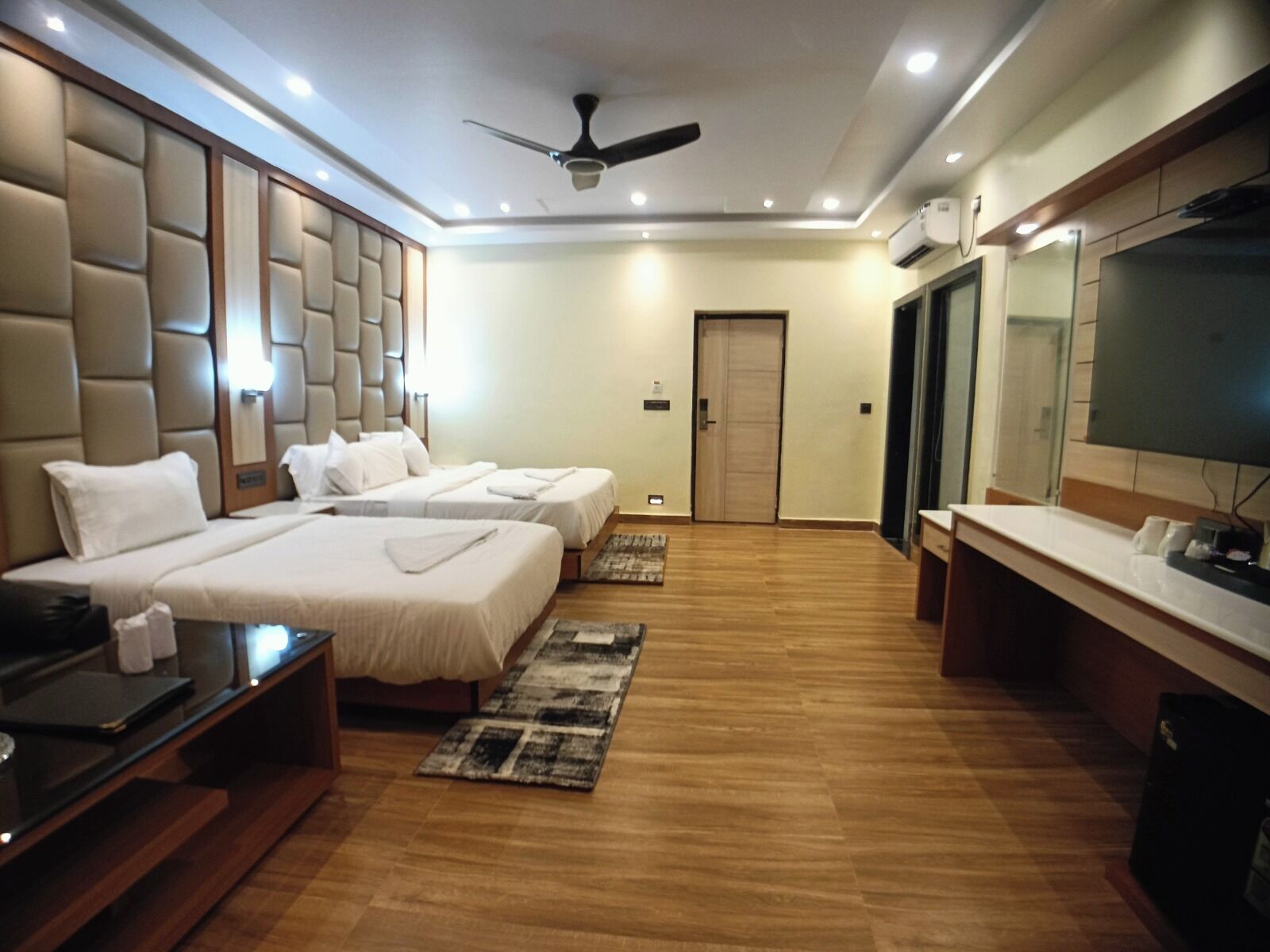 Une chambre d’hôtel avec deux lits, un ventilateur de plafond, une télévision et un mini-bar.