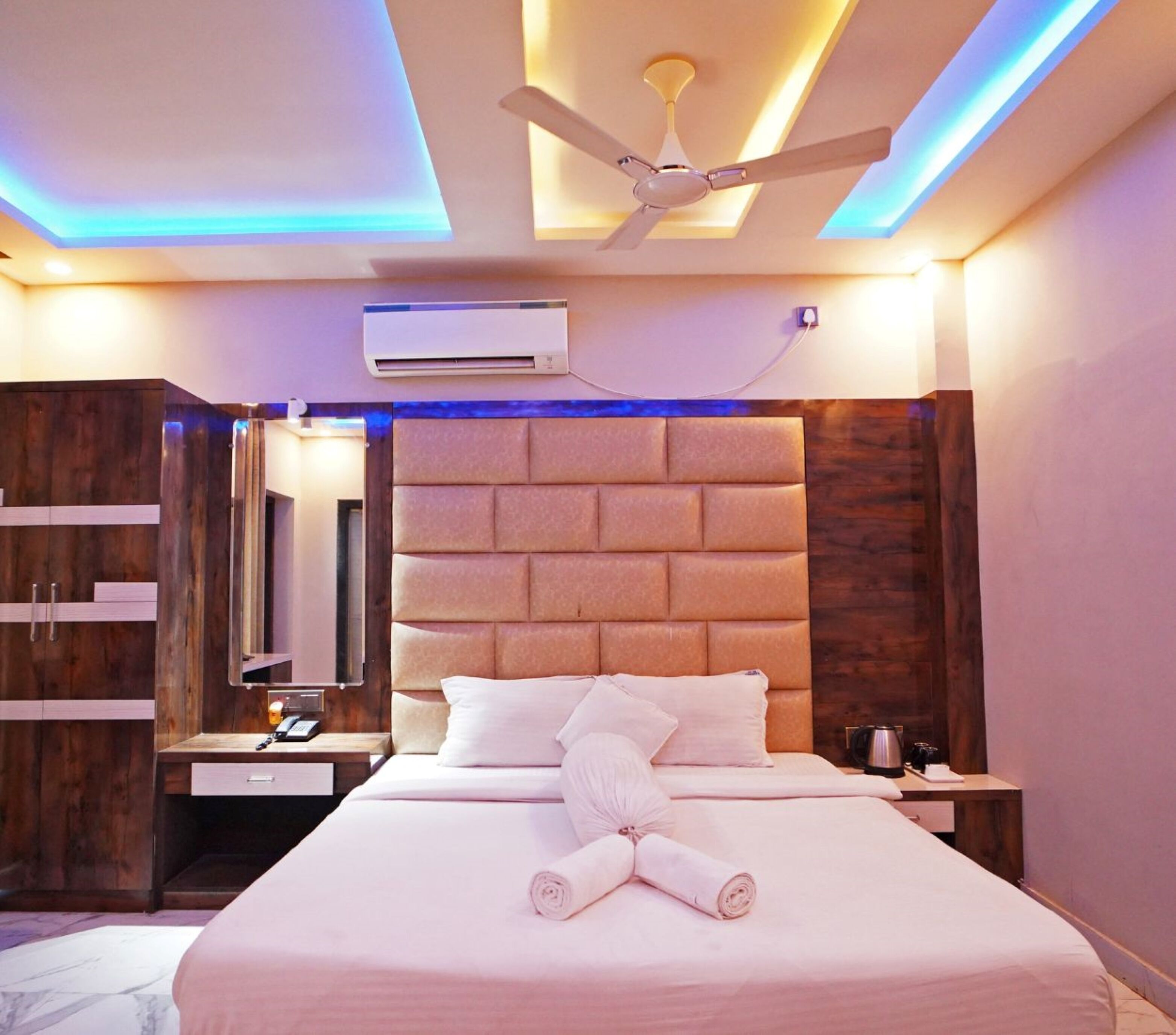 Ein modernes Hotelzimmer mit einem großen Bett, einem Deckenventilator, einer Klimaanlage und einem Holzschrank.