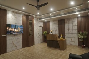 A reception area with a wooden reception desk, a television mounted on the wall, and a ceiling fan.