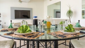 A modern dining area with a round glass table, multiple plates, cutlery, and glassware. - Villa Majum Ocean View Acapulco 5 BDR (Acapulco)