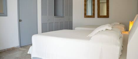 A bedroom with a bed, a wardrobe, and two mirrors on the wall.