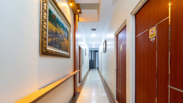 A hotel hallway with a tiled floor, wooden doors, and framed artwork on the walls. - Tebet Utara Suites (Jakarta)