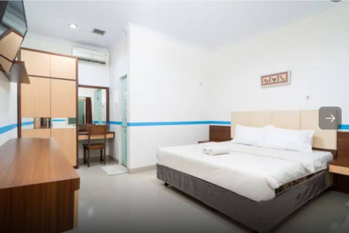 A hotel room with a bed, a desk, a chair, and a wardrobe.