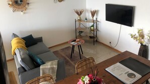 Een moderne woonkamer met een bank, een salontafel, een televisie en decoratieve objecten.