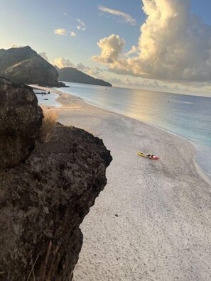 Una spiaggia con sabbia bianca, una scogliera rocciosa e un cielo sereno.