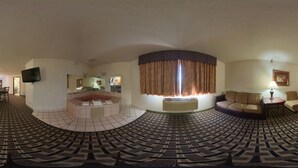 A panoramic view of a hotel room with a circular seating area, a flat-screen TV, a sofa, a table with a lamp, and a large window with curtains. - Blue Way Inn & Suites Minneapolis Airport Eagan - Mall of America (Eagan)