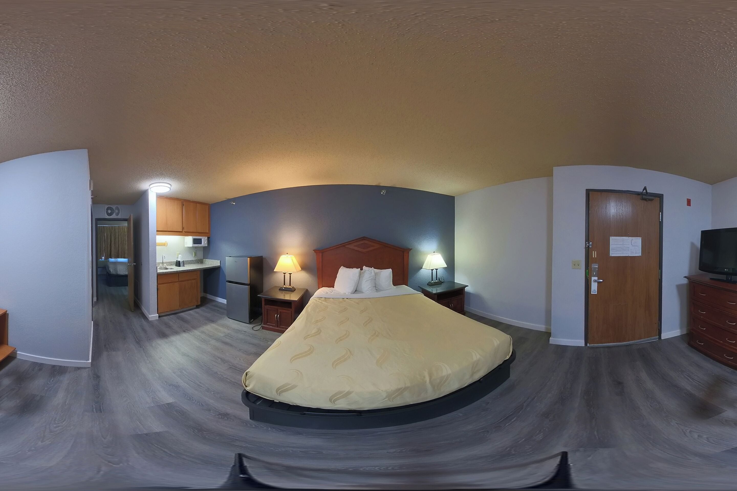 A hotel room with a bed, a desk, a chair, a TV, a wardrobe, and a door.