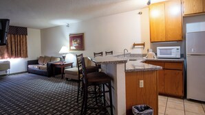 A compact living space with a kitchenette, a sofa, a dining area, and a patterned carpet. - Blue Way Inn & Suites Minneapolis Airport Eagan - Mall of America (Eagan)