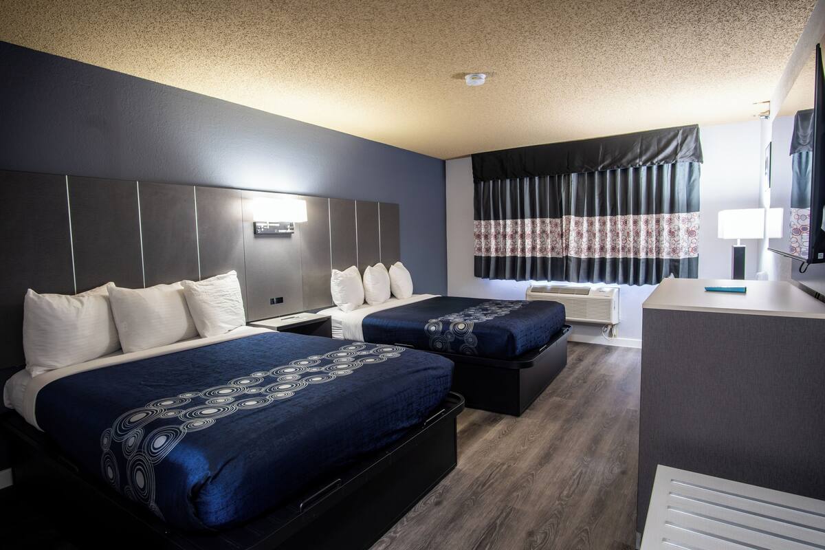A hotel room with two beds, a desk, and a large mirror.