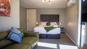 Een moderne hotelkamer met een groot bed, een groene bank en uitzicht op de omgeving.
