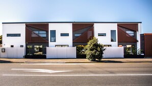 Een modern gebouw met een plat dak, grote ramen en een witte gevel.