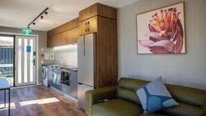 Een moderne woonkamer met een groene bank en een schilderij aan de muur.