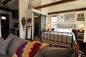 A bedroom with a metal bed frame, a sofa, and a quilt.
