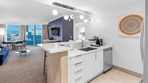 Ein modernes Hotelzimmer mit einer Küche, einer Essecke und einem großen Fenster mit Blick auf die Stadt.