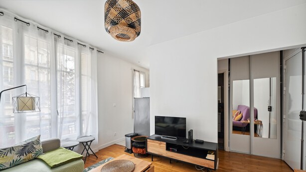 Un salon moderne avec un canapé, un téléviseur et une table basse en bois.