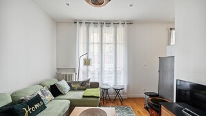 Un salon moderne avec un canapé, une table basse, un téléviseur et une fenêtre avec des rideaux.