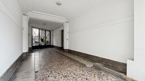 Un couloir au sol carrelé et aux murs blancs.