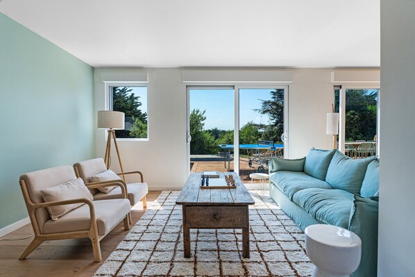 A living room with a wooden coffee table, beige sofas, and a blue couch.