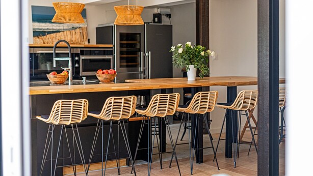 Une cuisine moderne dotée d’un îlot central, de tabourets de bar et d’un luminaire suspendu.