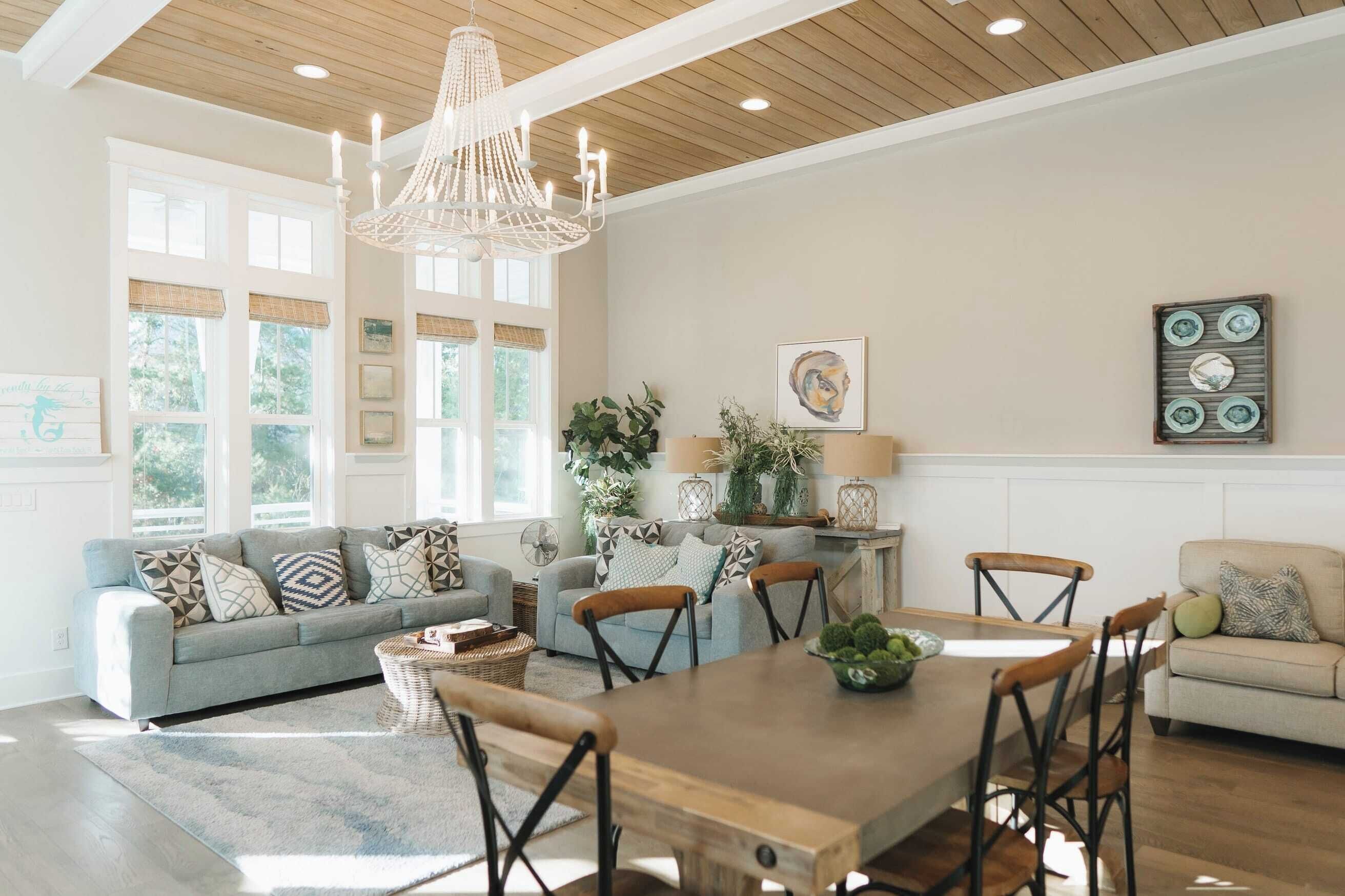 A spacious living room with a wooden dining table, two sofas, and a chandelier.