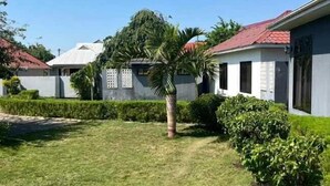 A residential area with houses, a well-maintained lawn, and a palm tree. - Marbella lodge  (Bagamoyo)