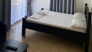 A bedroom with a bed, a ceiling fan, an air conditioning unit, and a window with curtains. - Marbella lodge  (Bagamoyo)
