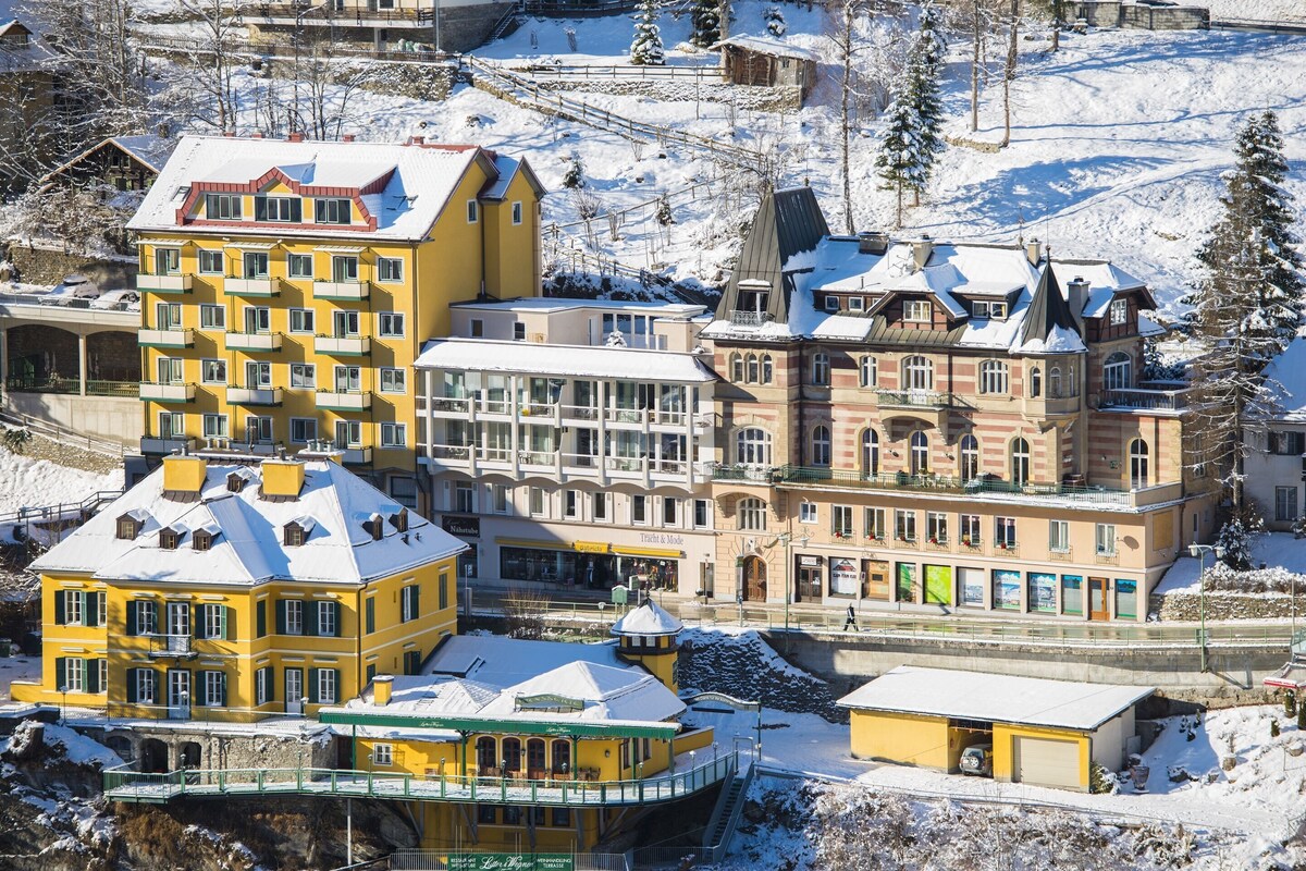 A multi-story hotel with balconies, a ski slope in the background, and a snow-covered landscape.
