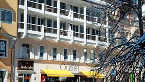 Ein mehrstöckiges Hotel mit Balkonen, ein Geschäft mit gelbem Markisenvorzelt und Schnee auf dem Dach.