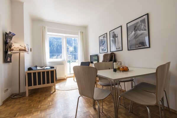 Un espace repas comprenant une table, des chaises et une vue sur un paysage enneigé par la fenêtre.