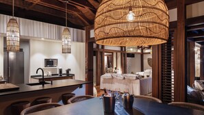 Una cocina moderna con una isla central, un comedor con una mesa grande y un dormitorio acogedor con cama y mesitas de noche.