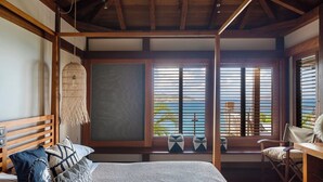 Una habitación con cama, lámpara colgante, ventana con persianas y vista al exterior.