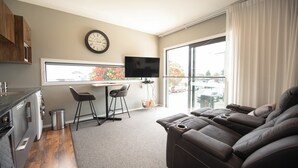 A modern living space with a kitchen, a dining area, and a large window offering a view of the outside. - The Residence Apartment Two (New Plymouth)